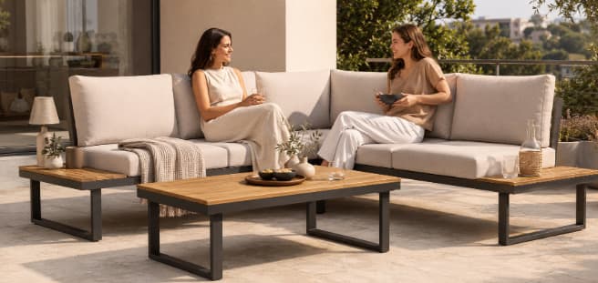 Zwei Frauen sitzen auf einer beigen Gartenlounge mit Tisch auf einer Terrasse